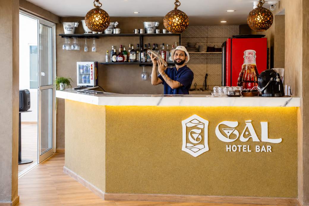 Balcão do bar do hotel com luzes pendentes e um atendente de plantão