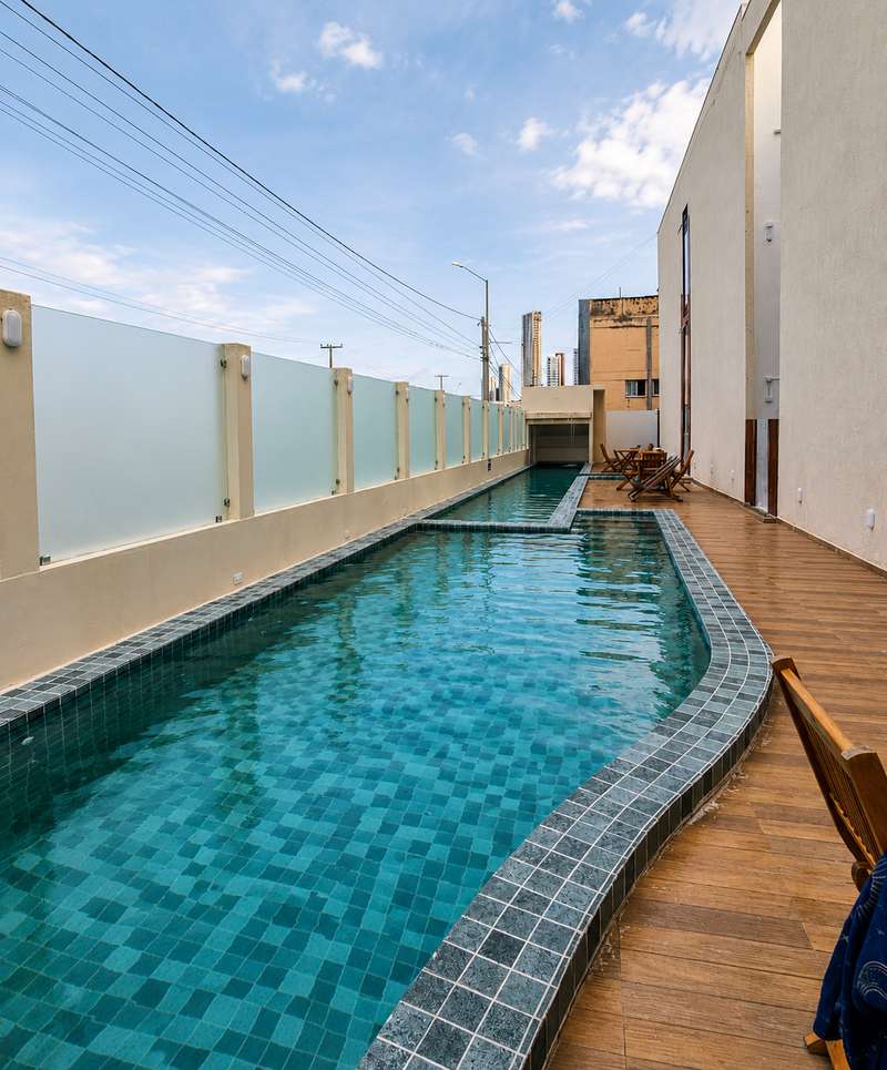 Piscina e deck de madeira com cadeiras no fim da tarde