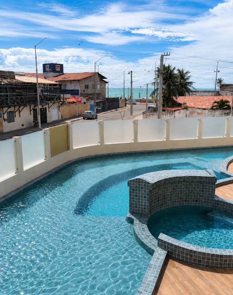 Piscina e deck com o mar visível depois da rua